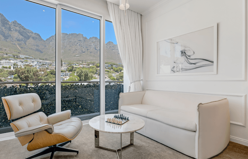 Deluxe Two-Bedroom suite lounge with Eames chair, chess set and floor-to-ceiling views of the Twelve Apostles mountain range