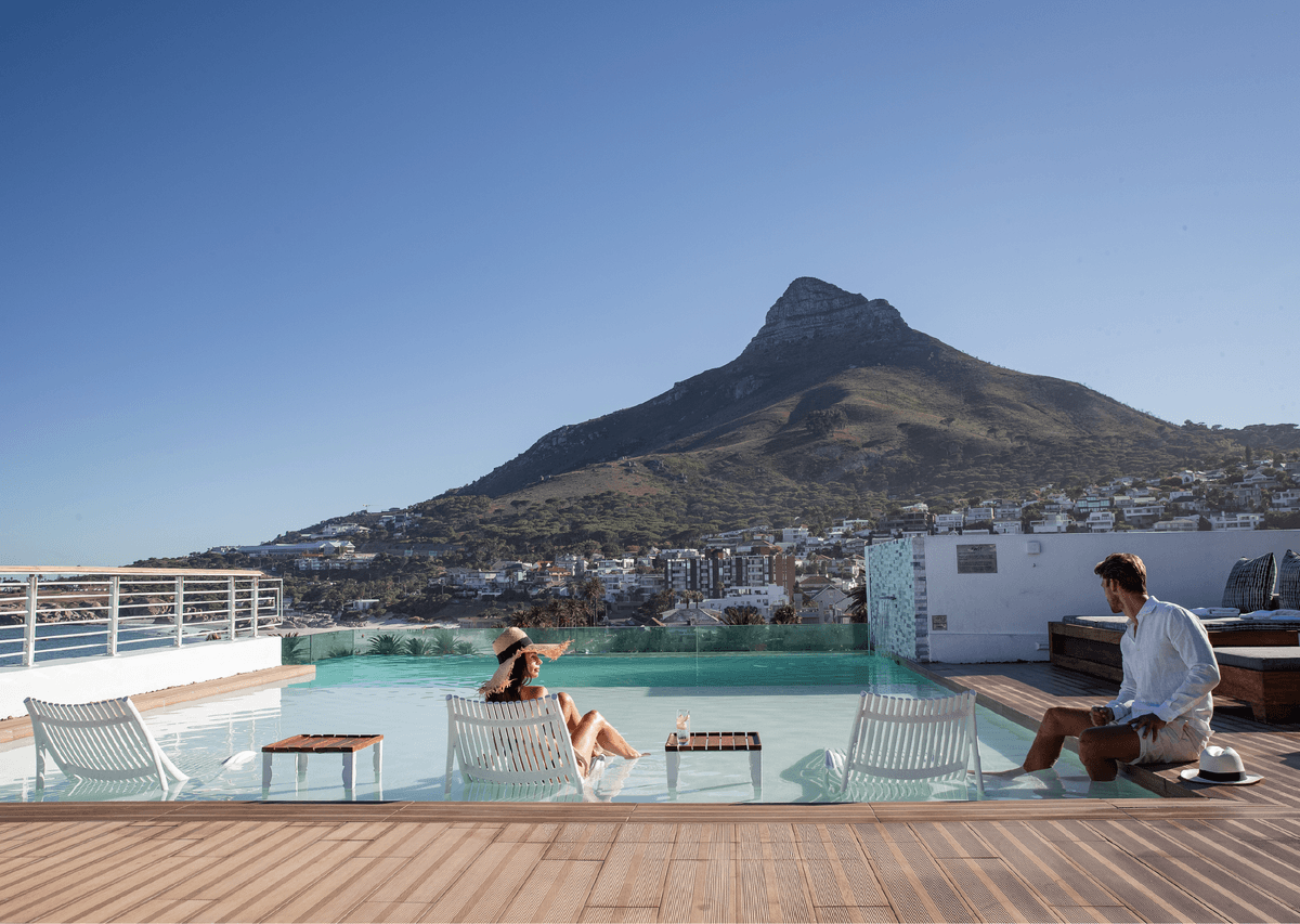 Couple relaxing in The Marly's rooftop infinity pool with Lion's Head mountain in the background