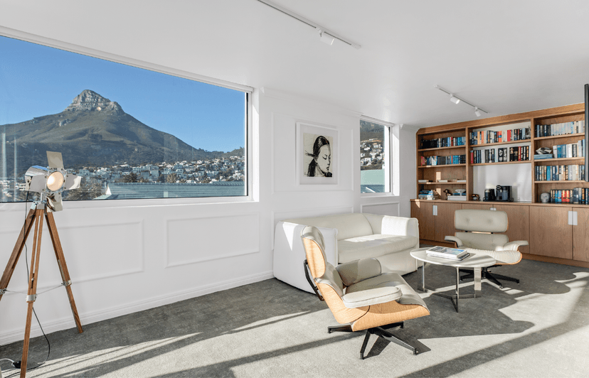 Junior Sea-Facing Suite living area with Lion's Head mountain view, built-in bookshelf and Eames lounge chair
