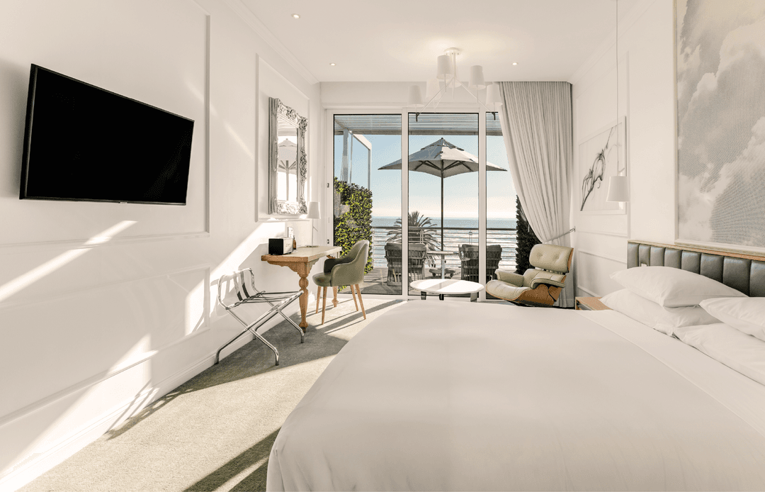 Studio Sea-Facing Room with king bed, work desk and sliding doors opening onto a sea-view balcony with umbrella
