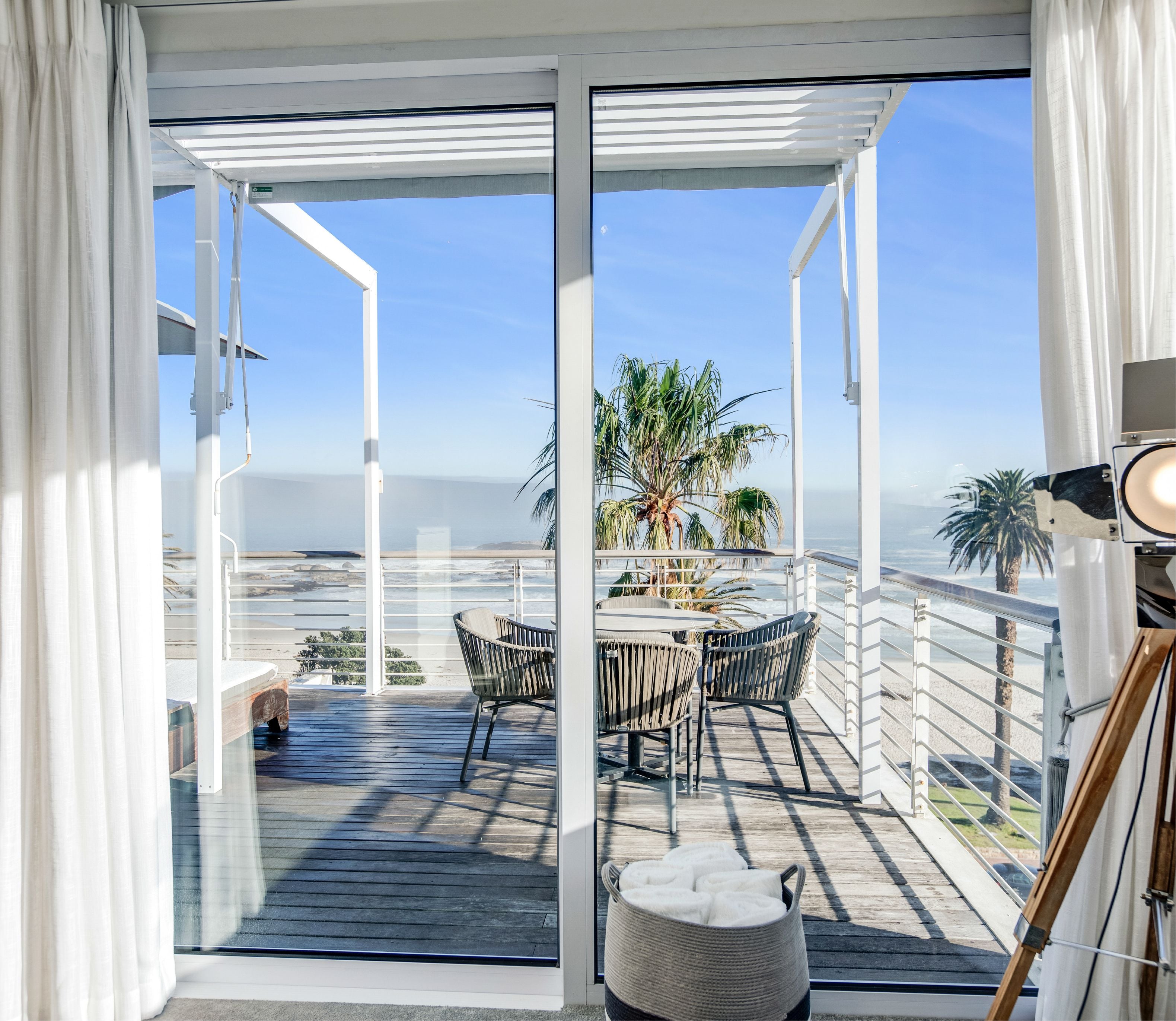 Ocean and palm tree view from the private balcony of a Junior Sea Suite at The Marly, Camps Bay