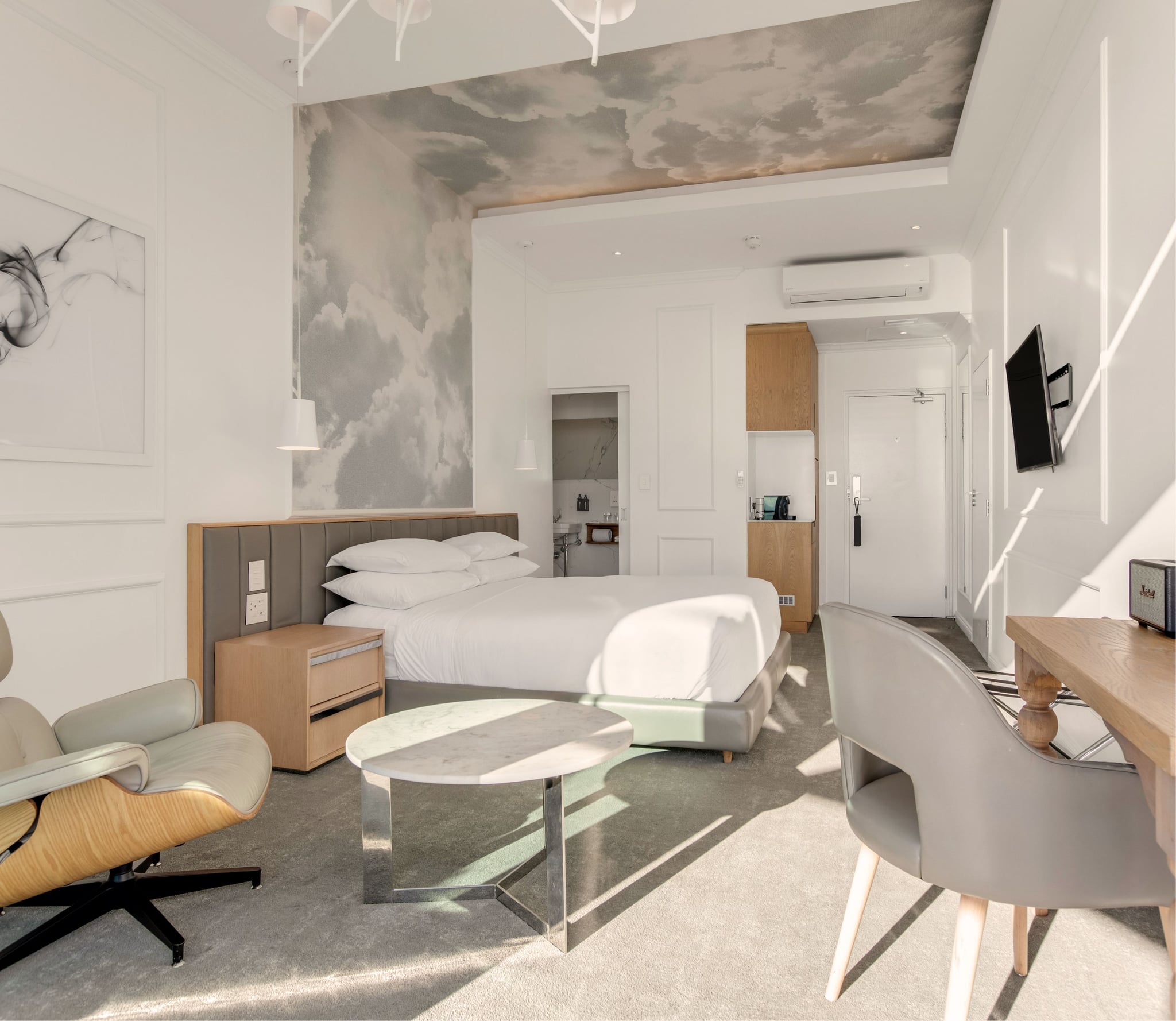 Studio Sea-Facing Room with cloud-mural ceiling, king bed, Eames lounge chair and en-suite bathroom entrance