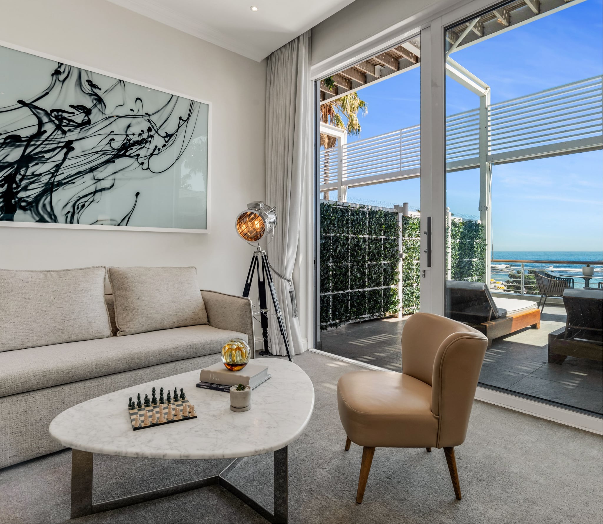 Superior Sea-Facing Suite bed with padded headboard facing a large abstract artwork and lounge seating