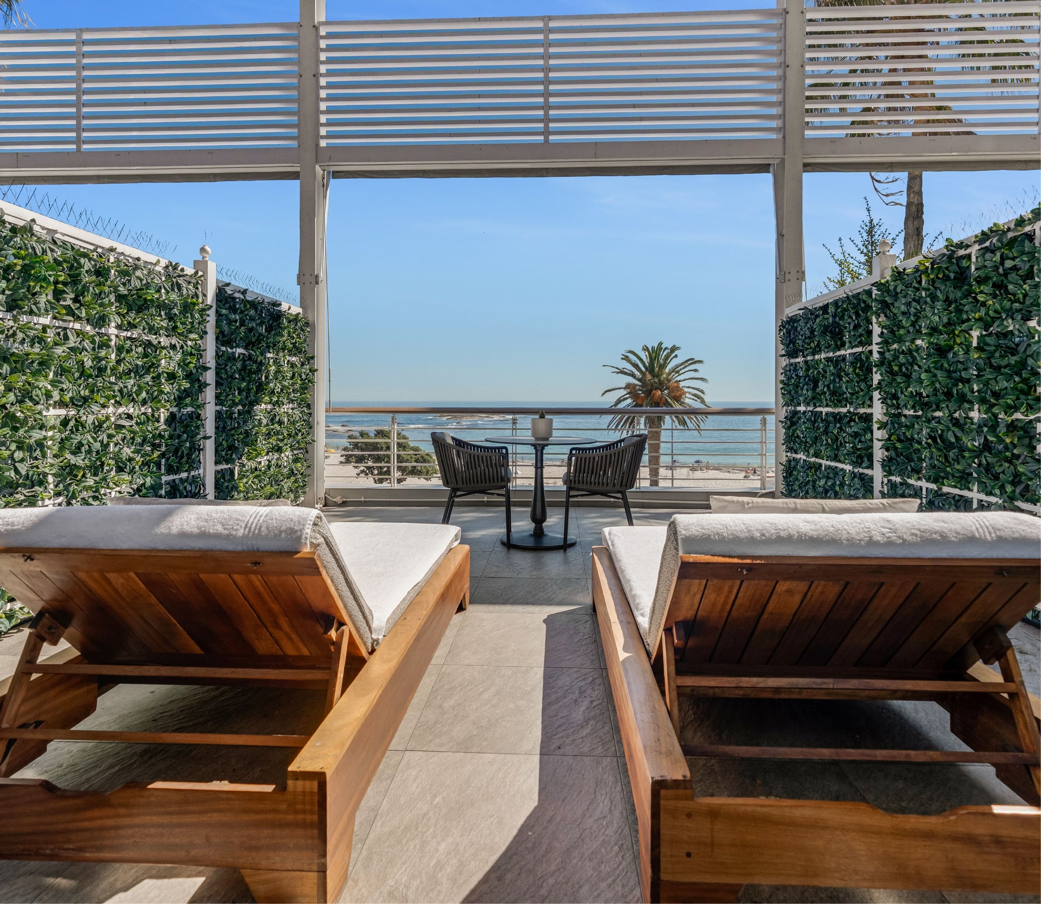 Superior Sea-Facing Suite living space with grey armchair, marble table and glimpse of the sea-view balcony