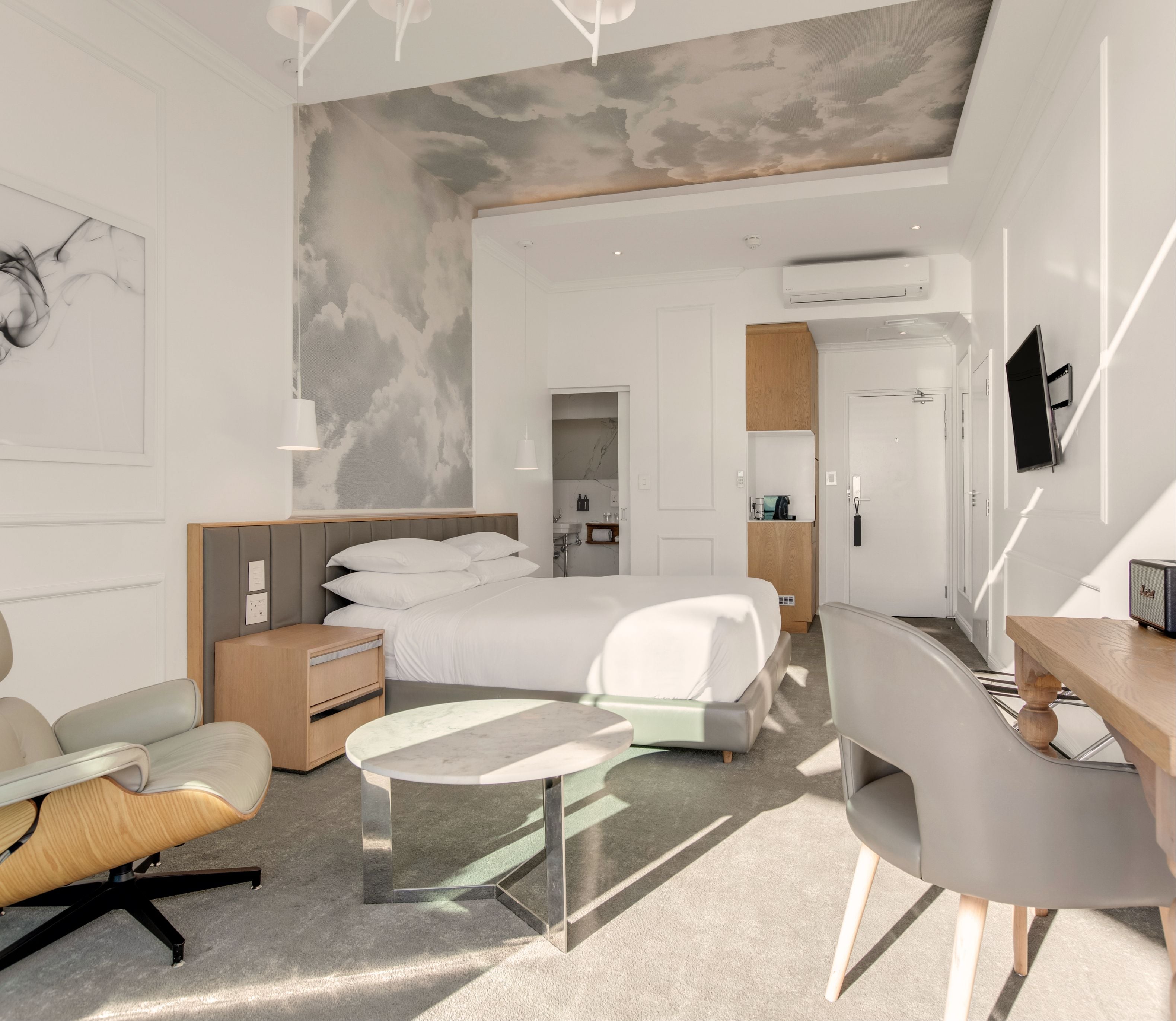 Studio Sea-Facing Room with cloud-mural ceiling, king bed, Eames lounge chair and en-suite bathroom entrance