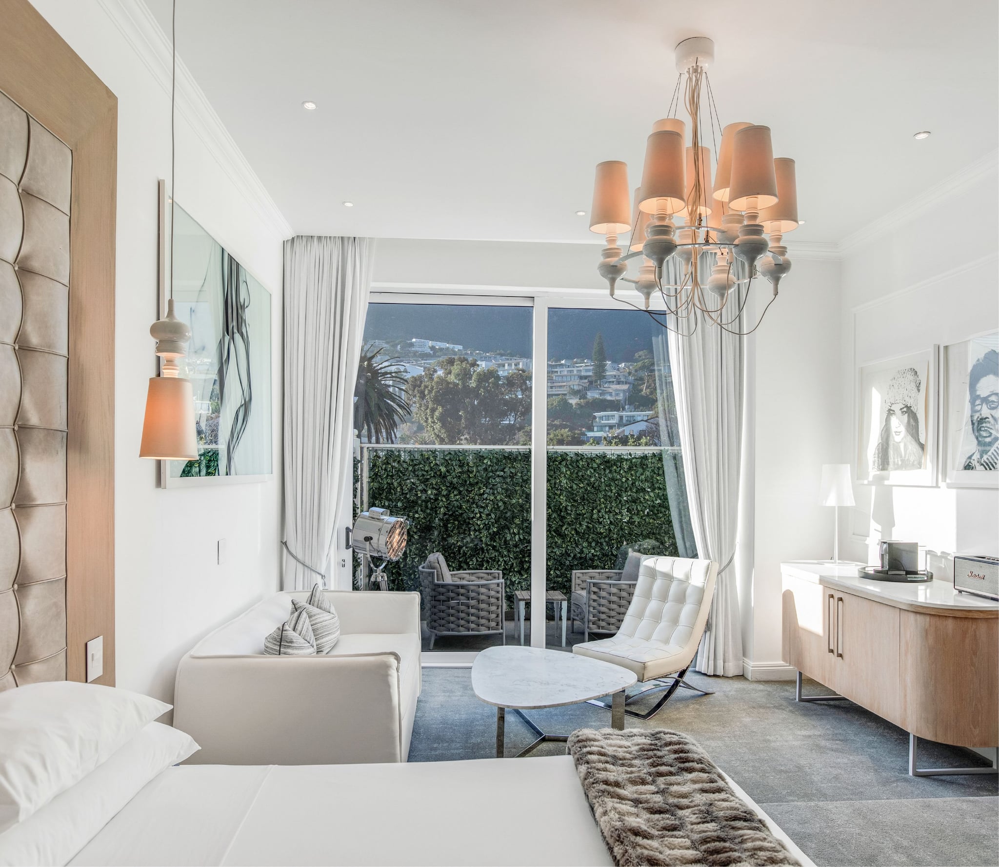 Superior Mountain Suite bedroom with tufted headboard, chandelier and sliding doors leading to a hedge-lined balcony