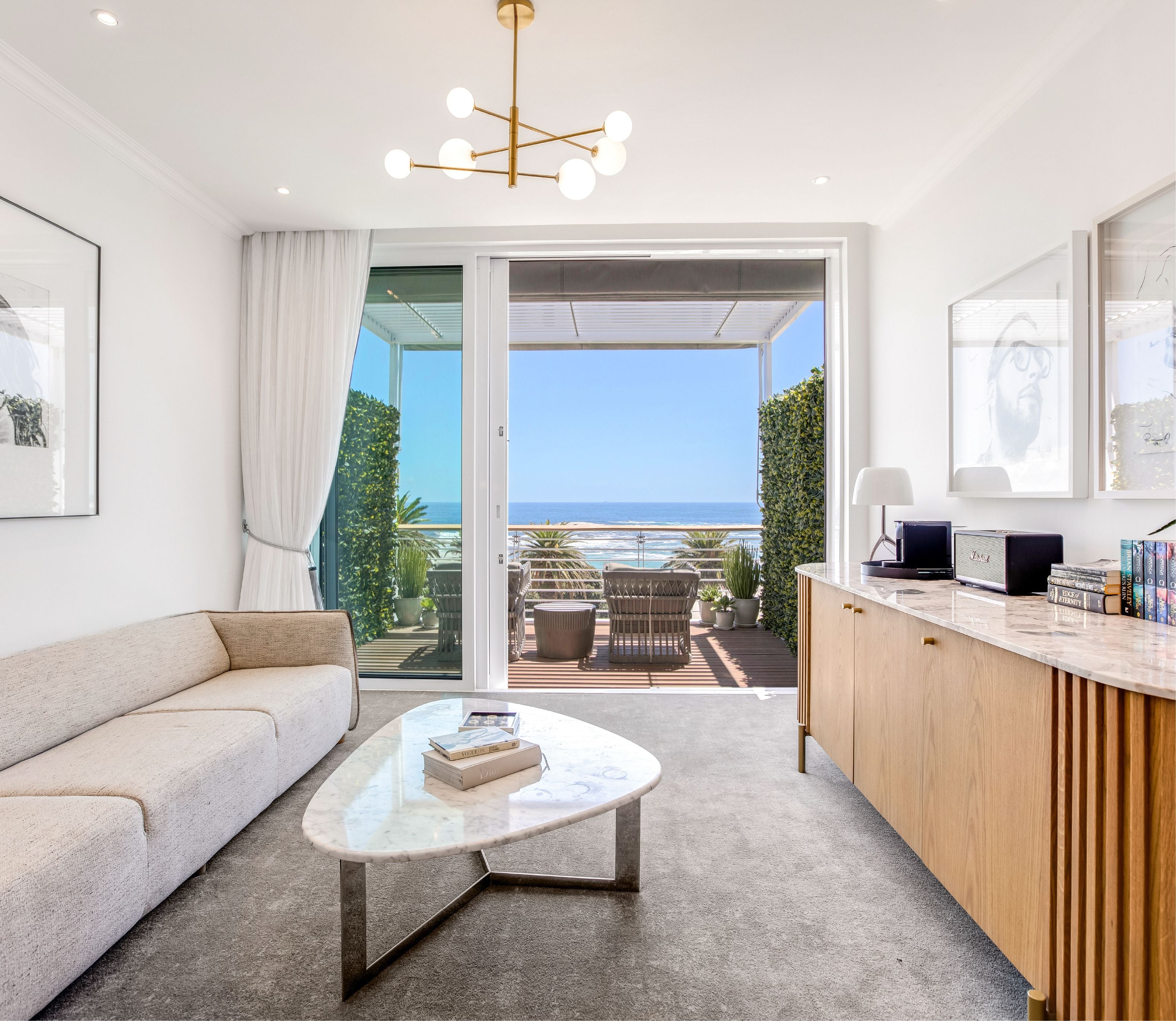 Superior Sea-Facing Room sitting area with sofa, marble coffee table and full ocean views through open balcony doors